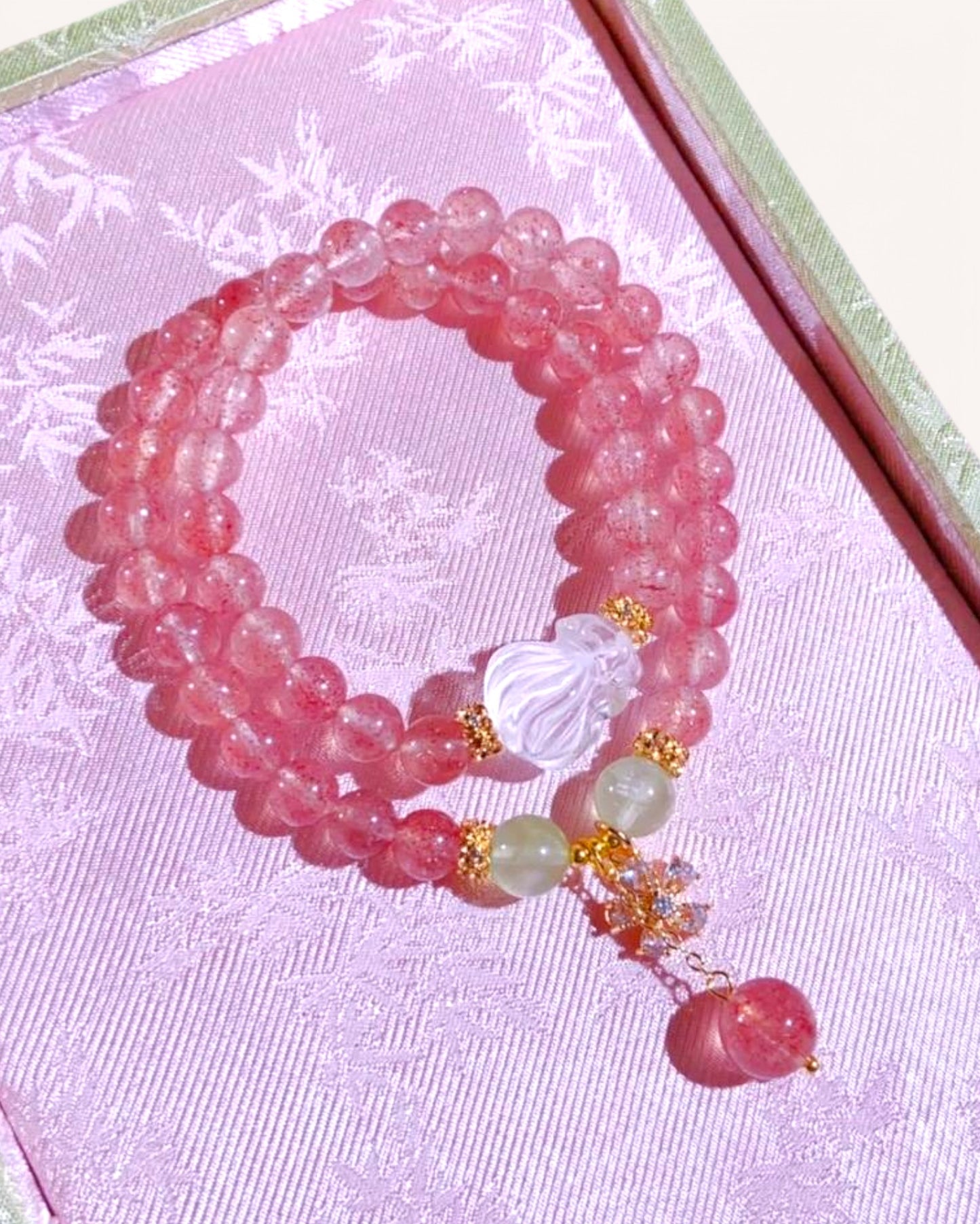 Close-up of Strawberry Quartz and White Quartz bracelet with Nine-Tailed Fox pendant, laid on a soft lilac velvet fabric to emphasize romantic and spiritual energy.