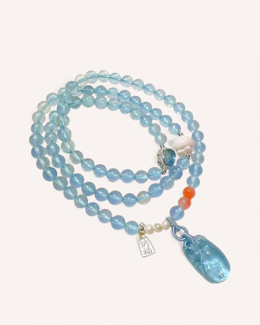 Aquamarine healing mala beads displayed with red agate and sterling silver charm for emotional healing