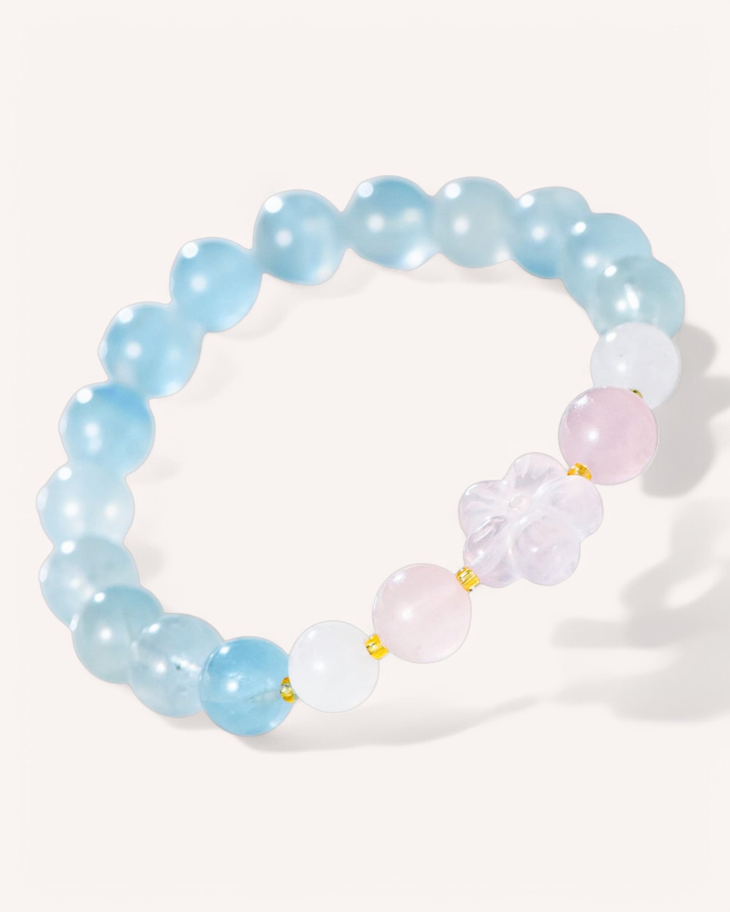 Side angle of aquamarine and rose quartz crystal bracelet with carved flower centerpiece for emotional balance and clarity