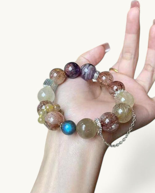 Model hand holding Black Gold Super Seven and Phantom Amethyst bracelet designed to attract wealth, align chakras, and enhance focus