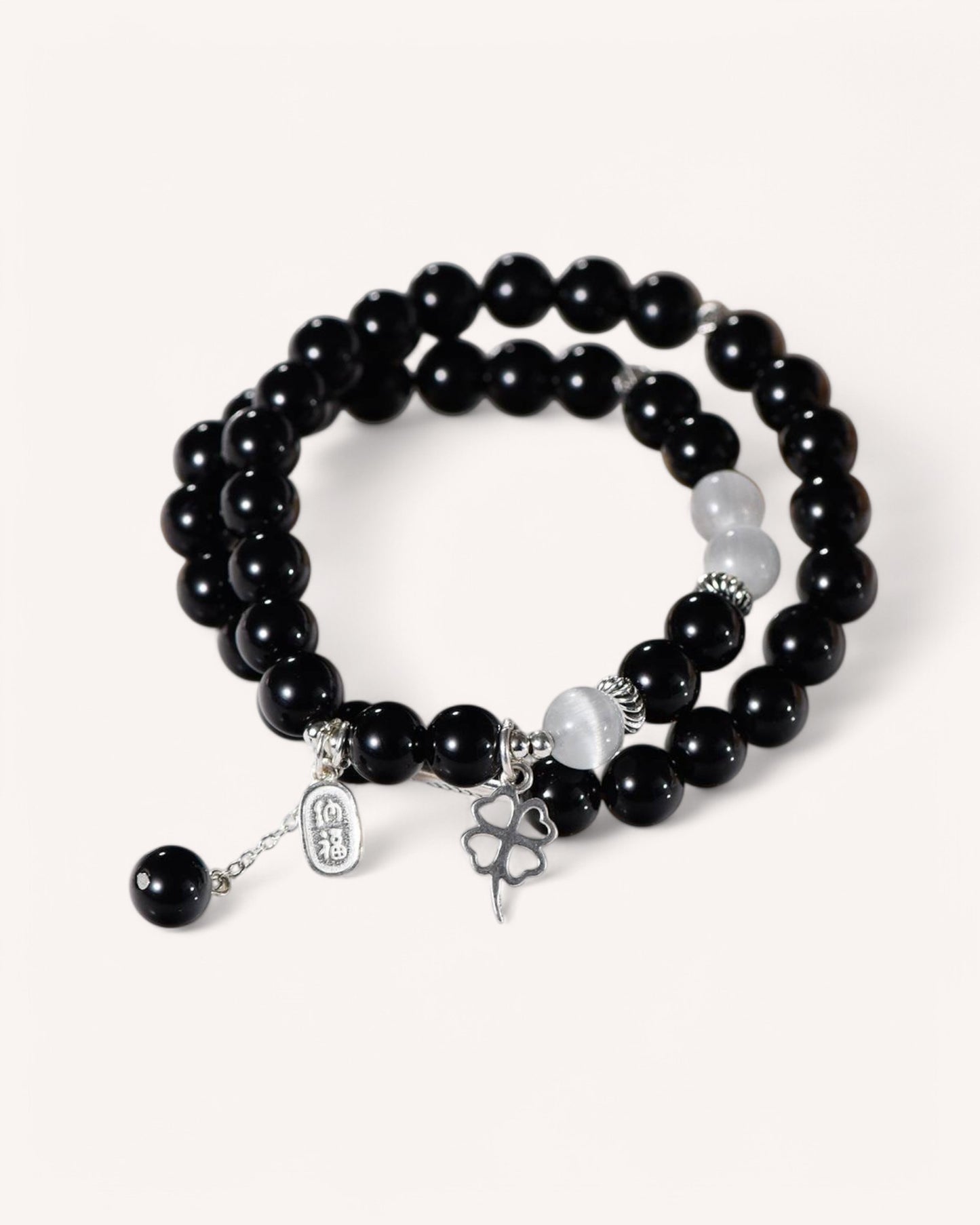 Curved side view of Cat’s Eye and Black Obsidian bracelet featuring silver prosperity talisman