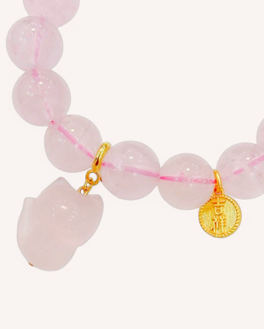 Close-up of rose quartz bracelet with fox charm and gold accent, symbolizing love, balance, and spiritual transformation.