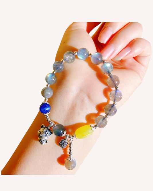 Kyanite and Moonstone bracelet with Amber bead and silver charms worn on wrist, symbolizing emotional healing and inner peace.