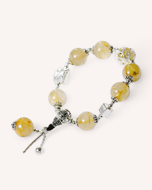 Flat lay of golden rutilated quartz bracelet designed for financial growth and motivation.