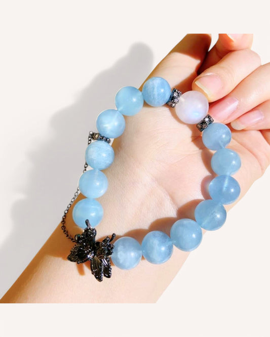 Woman wearing aquamarine and blue moonstone bracelet with butterfly detail for inner balance and intuition