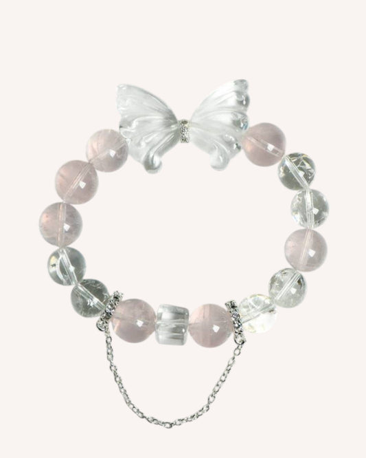 Close-up view of the Love & Clarity Rose Quartz Butterfly Bracelet, featuring soft pink rose quartz beads, clear white quartz accents, and an intricately carved butterfly charm symbolizing transformation and renewal.