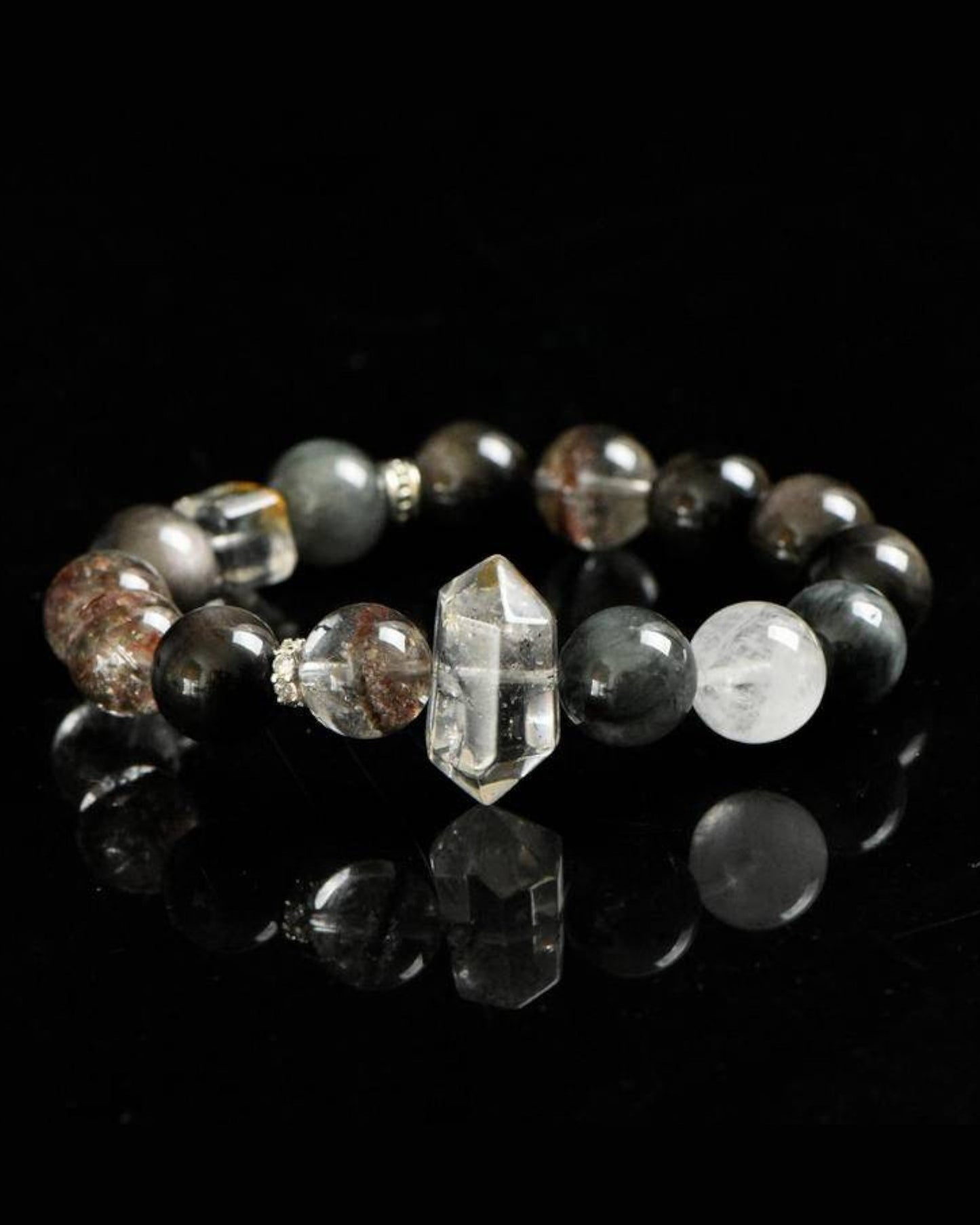 Energy protection and grounding bracelet with Phantom Quartz and Hawk’s Eye beads placed on a reflective black background.