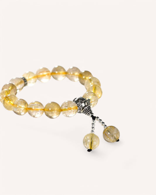 Side view of Rutilated Quartz crystal bracelet with silver charm, ideal for manifesting success and clearing obstacles.