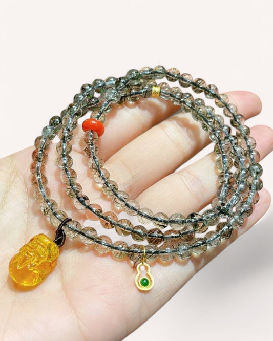 Hand holding a Black Gold Super Seven and Amber multi-layer bracelet with Red Agate, showcasing its rich spiritual energy and craftsmanship.