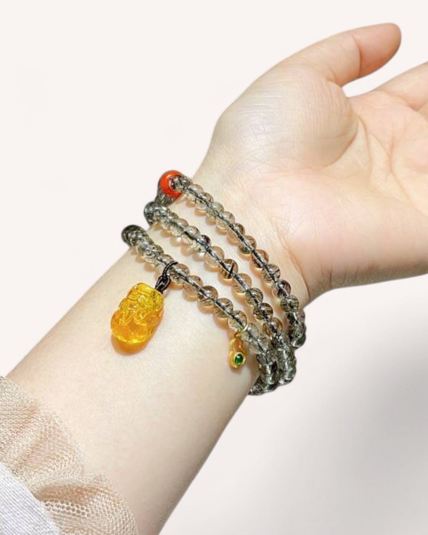 Wrist wearing a multi-layer Black Gold Super Seven and Honey Amber bracelet, ideal for confidence, grounding, and abundance.