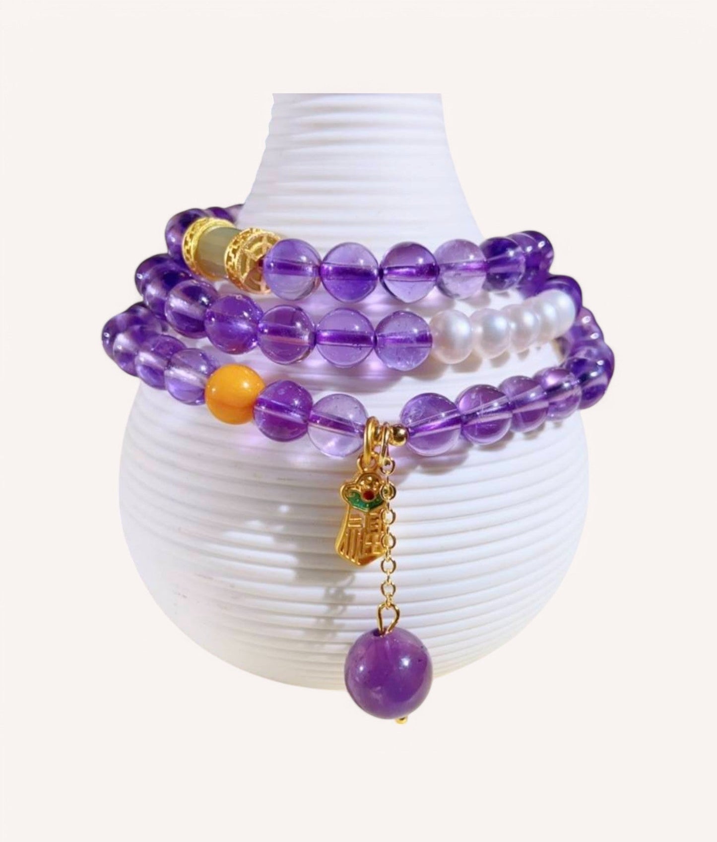 Amethyst & Honey Amber Prosperity Wrap Bracelet elegantly displayed on a decorative vase, showcasing its multi-layered design for abundance and emotional balance