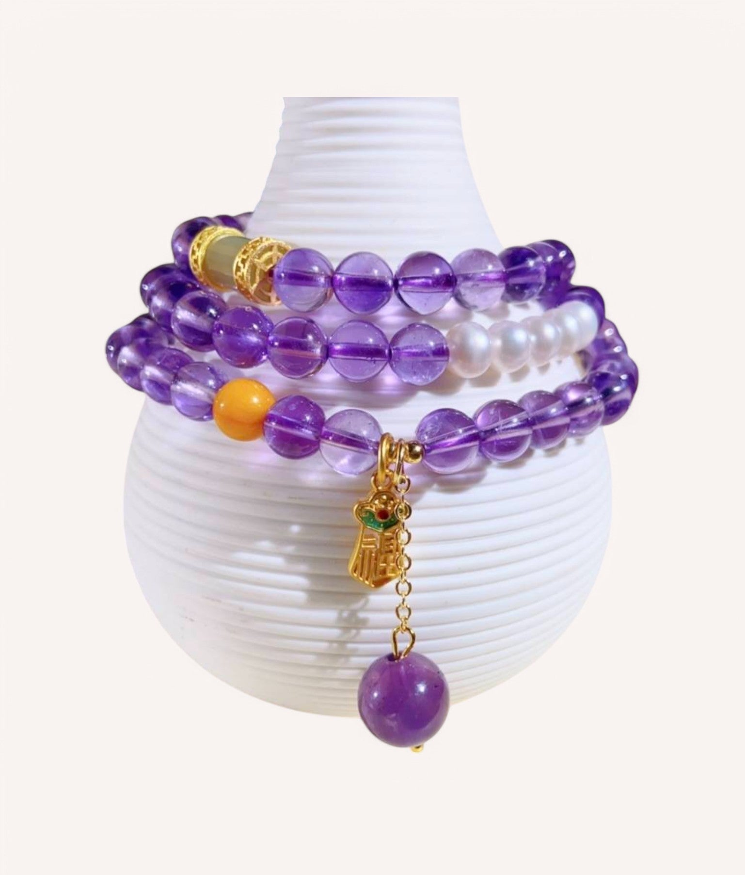Amethyst & Honey Amber Prosperity Wrap Bracelet elegantly displayed on a decorative vase, showcasing its multi-layered design for abundance and emotional balance
