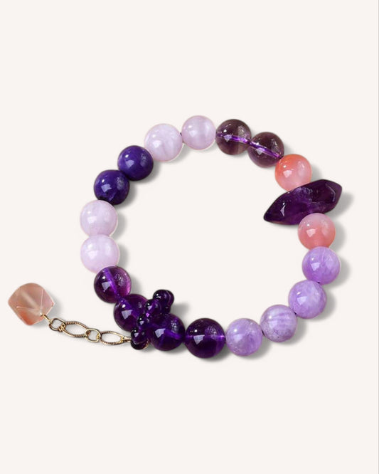 A radiant amethyst, kunzite, and purple agate bracelet featuring a deep purple crystal centerpiece, designed to enhance emotional healing, intuition, and self-love.