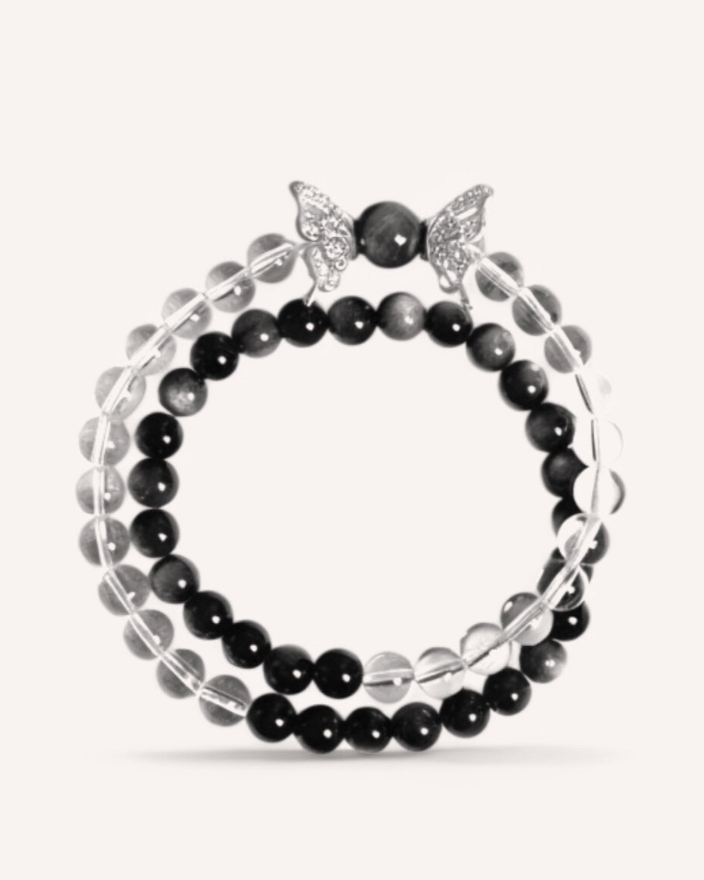A dual-layer White Quartz and Obsidian bracelet featuring an elegant butterfly charm. This piece promotes mental clarity, shields against negativity, and supports emotional grounding.