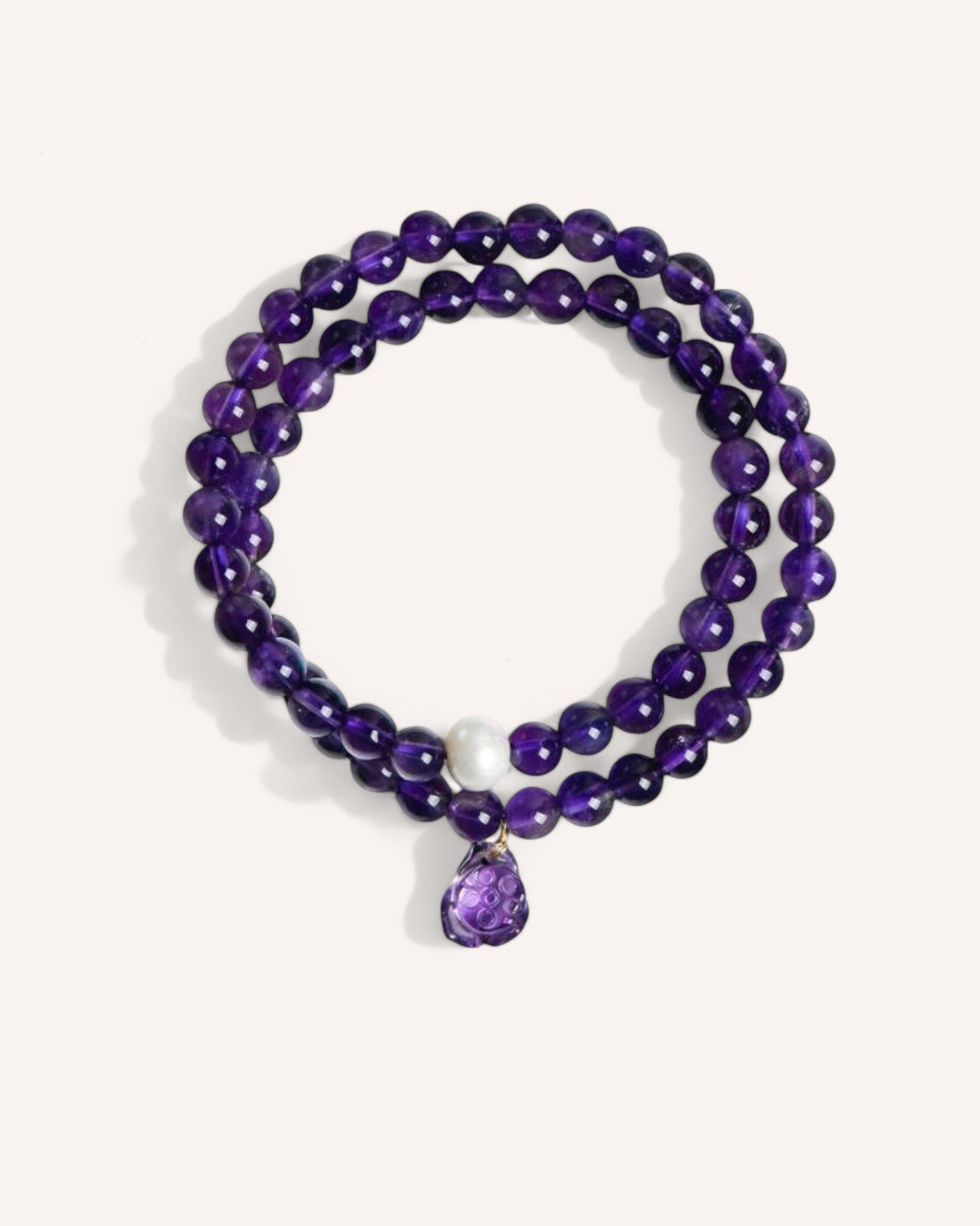 Handcrafted Amethyst Gemstone Bracelet with a double-wrap design, promoting inner peace, meditation, and emotional clarity. Accented with a white jade bead and an amethyst charm.