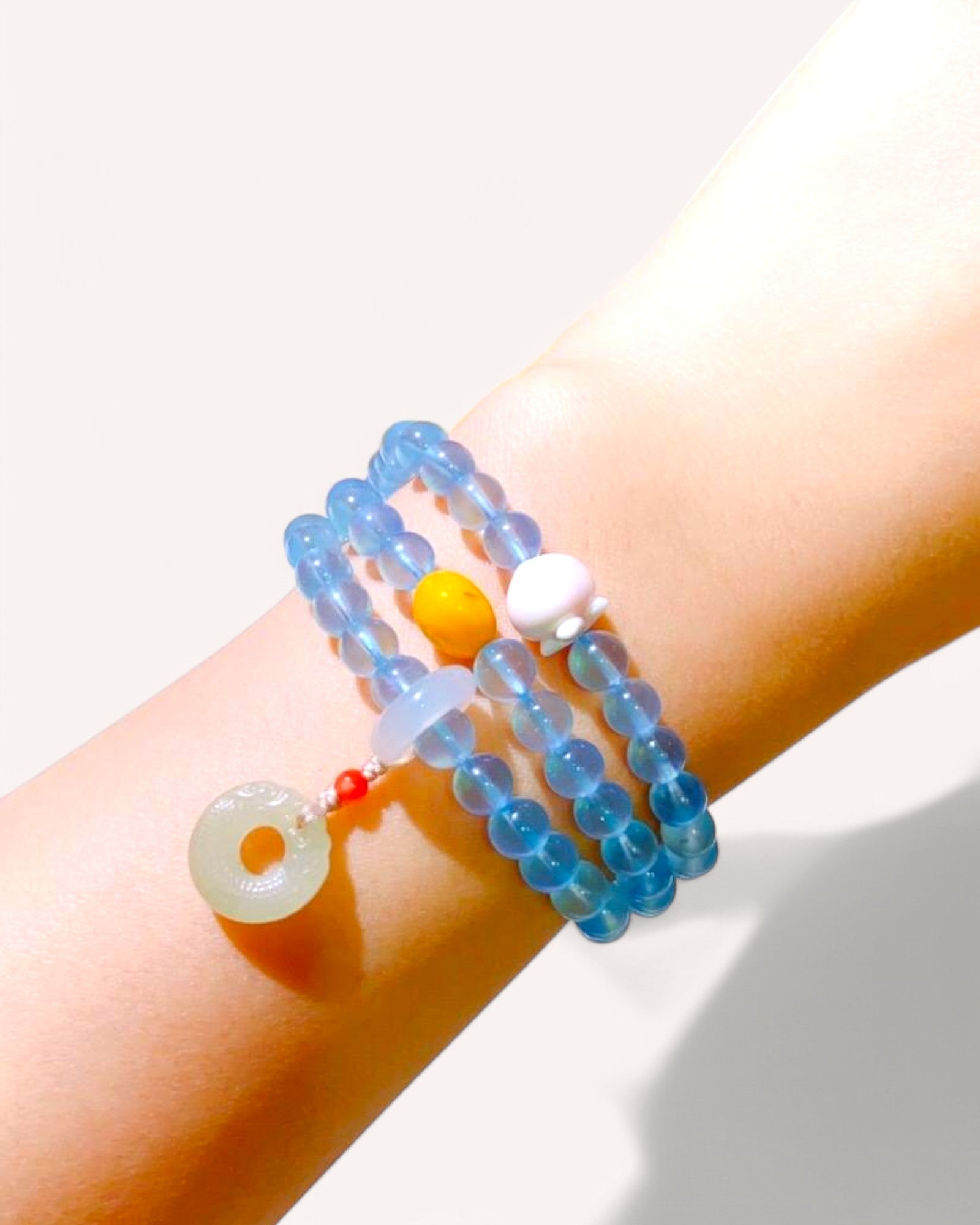 Model wearing aquamarine, amber, and jade triple-wrap bracelet for emotional stability and healing energy.
