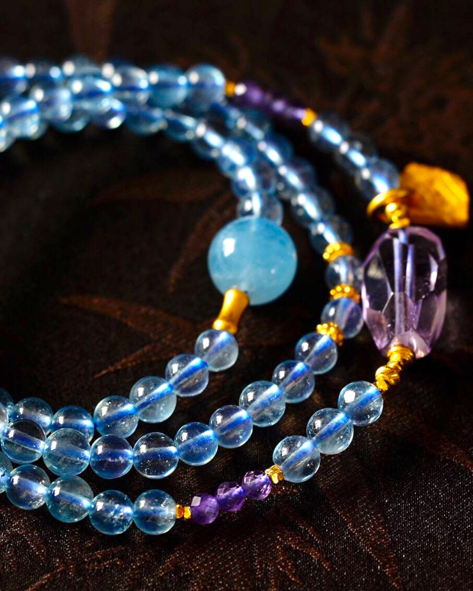 Close-up of aquamarine and amethyst wrap bracelet on wooden background, featuring calming gemstone energy