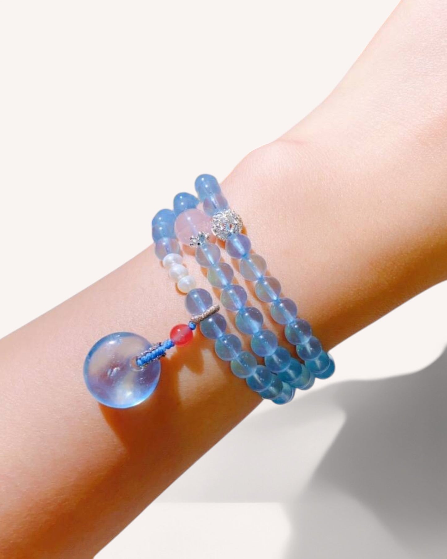 Model wearing a triple-wrap Aquamarine and Rose Quartz bracelet, symbolizing calmness, self-love, and inner peace.