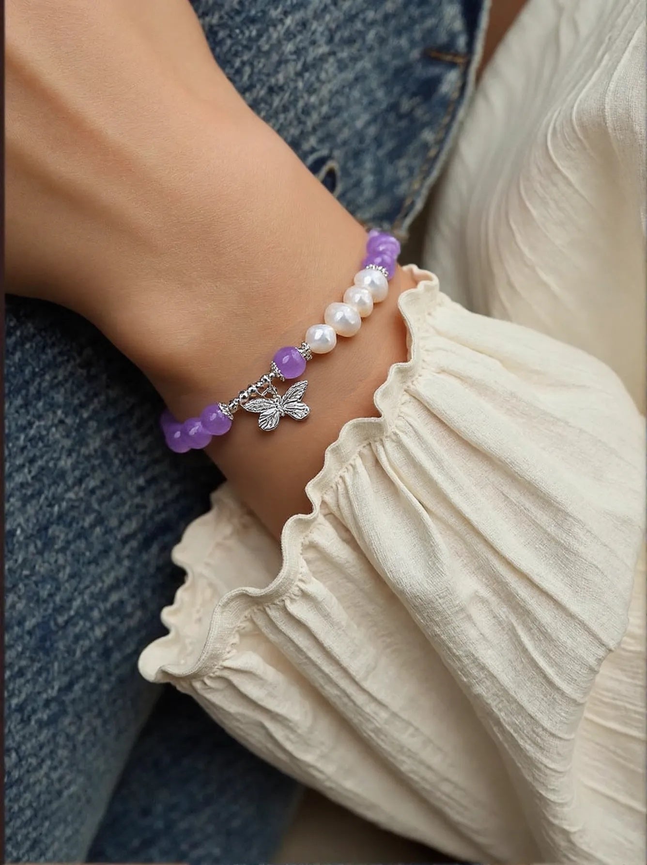 Close-up of a handcrafted Amethyst & Pearl Bracelet with a butterfly charm, designed to promote emotional balance, clarity, and transformation. Ideal for mindfulness and self-expression.