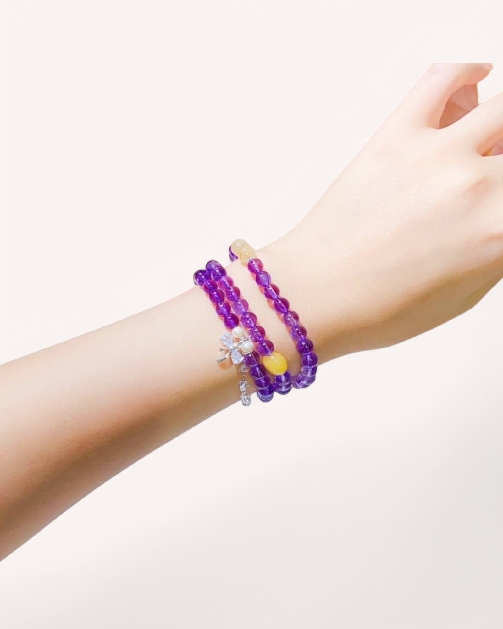 Elegant amethyst and moonstone triple-wrap bracelet worn on hand, promoting inner wisdom, emotional healing, and divine feminine energy.
