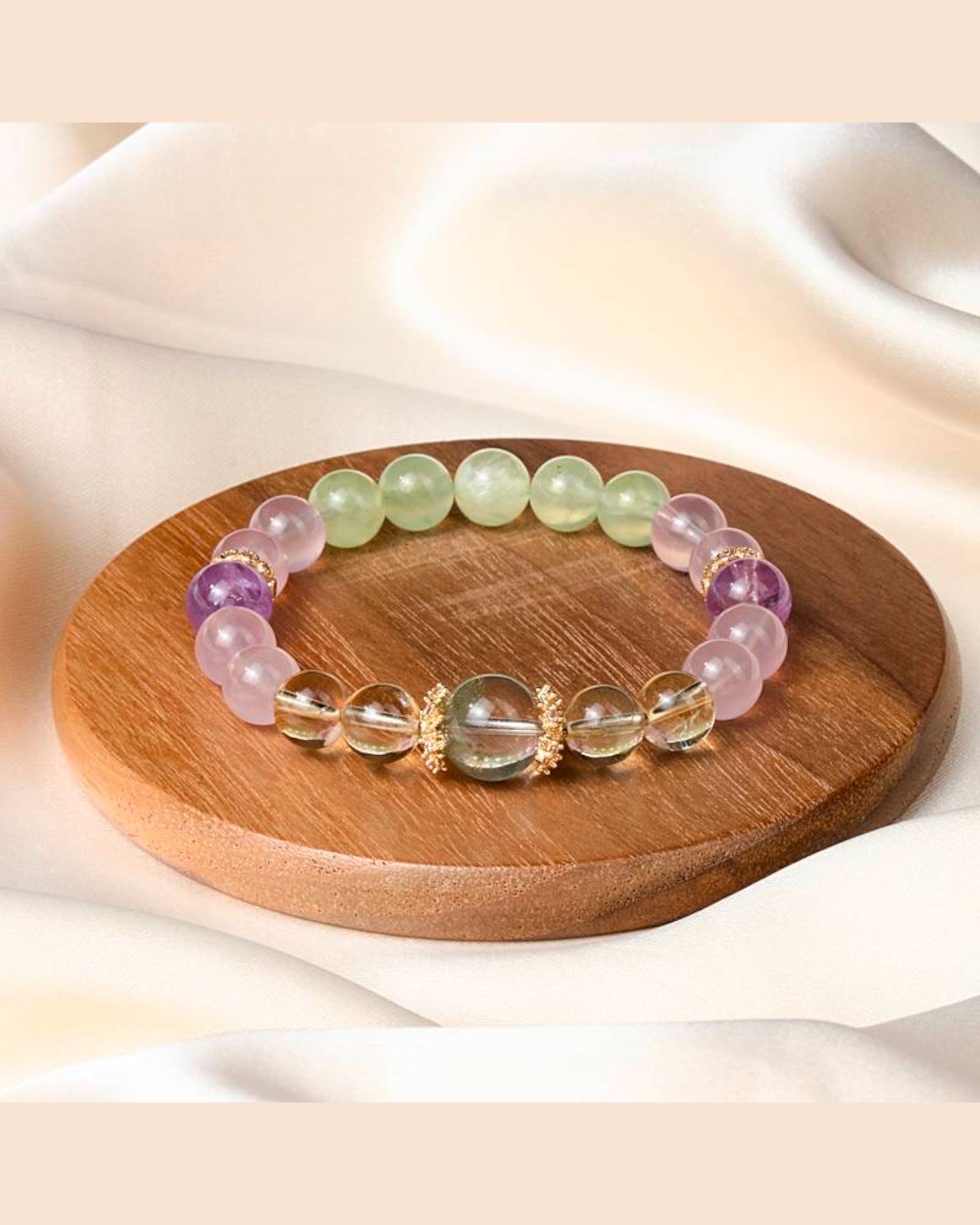 A Harmony & Protection Crystal Bracelet displayed on a wooden tray, crafted with White Quartz, Amethyst, Rose Quartz & Prehnite for emotional balance & spiritual wisdom.